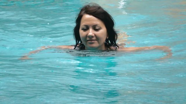 video of a attractive woman swimming in the pool.  People 4K Stock Footage Clip.
