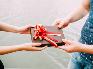 Couple giving a gift box to each other. Happy relationship in outdoor scene. Love and relationship concept