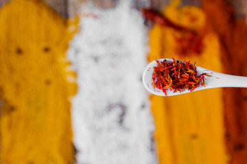 White spoon with saffron on different colorful spices background.  Various spices selection. Closeup. Copy Space