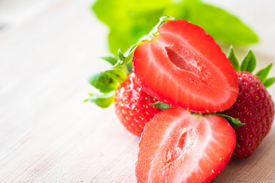 Pile of fresh strawberries on a wooden table.