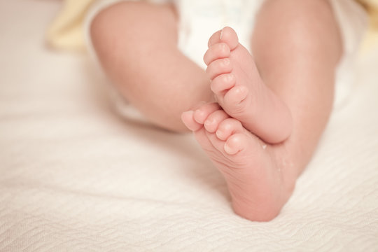 Newborn baby feet on bed in vintage color filter