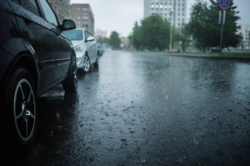 Heavy rain hitting a concrete sidewalk while cars parking