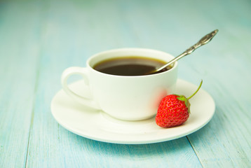 A cup with a drink and a strawberry on a blue
