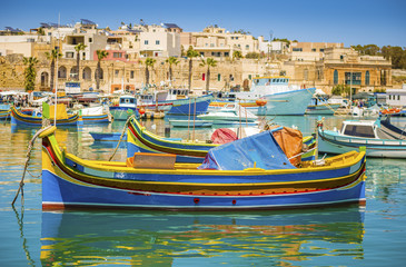 Malta - Colorful traditional Luzzu fishing boat at Marsaxlokk on a sunny summer day with green sea and blue sky