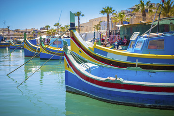Fototapeta na wymiar Malta - Colorful Mediterranean traditional Luzzu fishing boat at Marsaxlokk on a sunny summer day with green sea