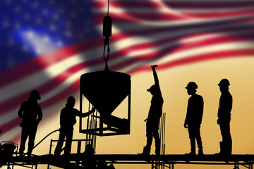 silhouette of construction worker stand on scaffolding framework casting concrete column in construction site blur United States flag background