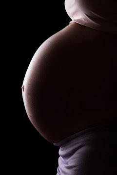 Pregnant woman in profile isolated on  black background.