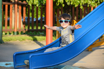 enjoy life, smiling boy with sunglasses enjoys sliding down a toboggan 