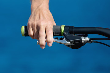 Close up bicycle rider's hands on a bicycle handlebar in the background of the sea.