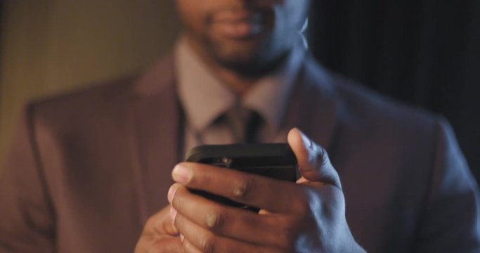 Close up on African American business man's hands and then tilt up to his face as he uses a smart phone.  Slow motion recorded at 60fps.