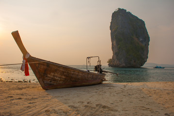 Fototapeta premium Long tail boat on tropical beach with limestone rock. Sunset, island Taming. Krabi, Thailand.