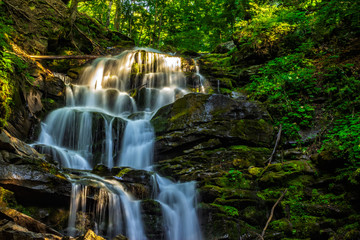Obrazy  piękny wodospad wyłania się z ogromnej skały w lesie