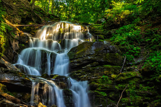 Fototapeta piękny wodospad wychodzi z ogromnej skały w lesie