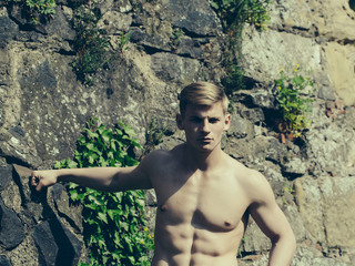 Muscular guy on stony wall backdrop