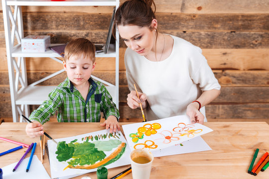 Cute little boy and his mother paiting bright pictures together