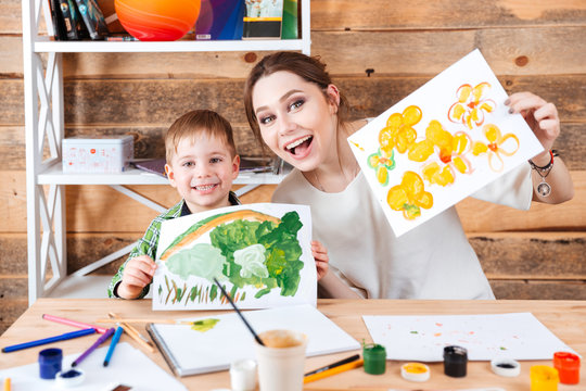 Happy cute little boy and his mother showing their paints