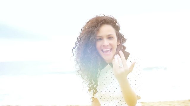 Young woman with beautiful curly hair gesturing follow me and running on the beach, slow motion