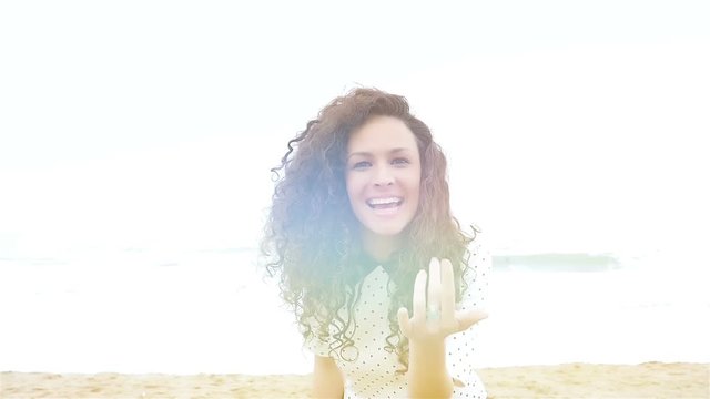 Young woman with beautiful curly hair gesturing follow me and running on the beach, slow motion