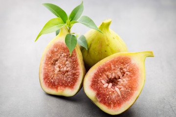 Whole figs and one fig sliced in half on top of a gray table.