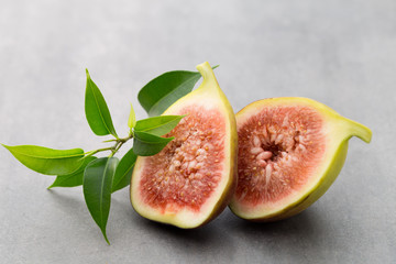 Whole figs and one fig sliced in half on top of a gray table.