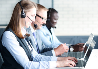 Portrait of call center worker accompanied by her team. Smiling customer support operator at work.