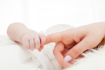 Newborn baby grasping her mother's finger. Child care, parent love.