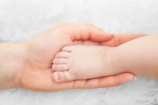 Newborn baby foot in mother's hand. Child care, love, protection