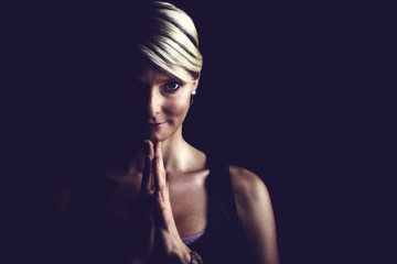Fototapeta na wymiar Lowkey Portrait von einer Frau mit gefallteten Händen Yoga mit Textfreiraum