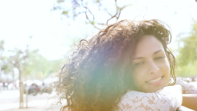 Romantic portrait of happy young woman with beautiful curly hair in summer, slow motion