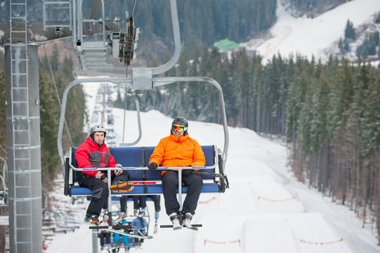 Skier and snowboarder riding up to the top of the mountain on ski lift, with beautiful view nature