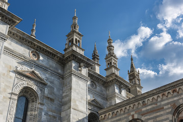 Fototapeta na wymiar Cathedral Spires of Como, Italy: The ornate late Gothic spires of the Duomo in Como rise into a beautiful blue and white sky of spring
