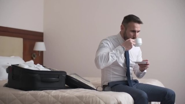 Businessman drinking coffee and smiling in his room in the hotel