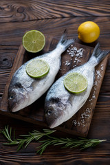 Two fresh uncooked sea breams with condiments