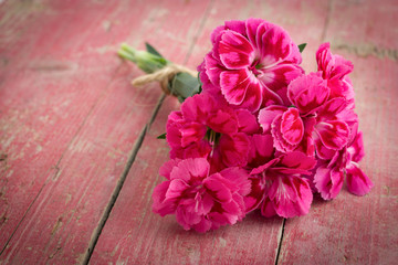 Bouquet of purple carnations on pink wooden background