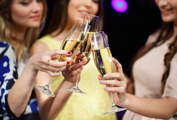 Clinking glasses of champagne in hands on bright lights backgrou