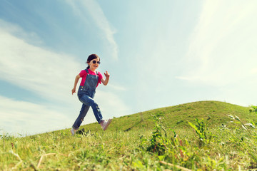 Naklejka na ściany i meble happy little girl running on green summer field
