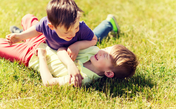 happy little boys fighting for fun on grass
