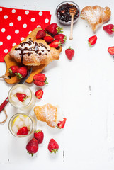 fresh croissants with lemonade and strawberries on white wooden background
