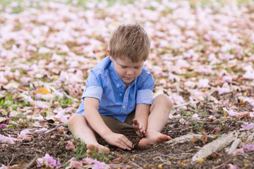 Little boy playing in dirt surrounded by flowers