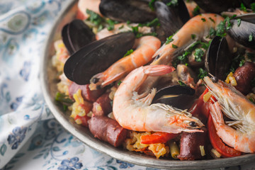 Paella in the metal plate on the  beautiful napkin horizontal