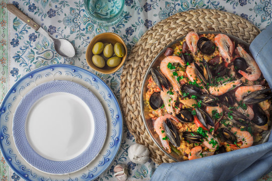 Paella on the metal plate on the beautiful napkin with tableware top view