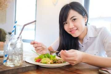 Young woman eating salad and meat meal