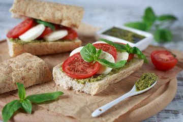 Fototapeta na wymiar Closeup of a fresh sandwich with mozzarella, tomatoes, pesto and