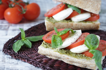 Closeup of a fresh sandwich with mozzarella, tomatoes, pesto and