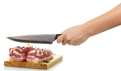 Raw pork with spices on  cutting board, hand holding  knife.