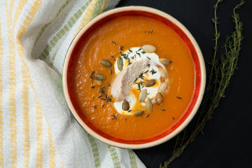 Pumpkin cream soup with chicken fillet, thyme and pumpkin seeds.