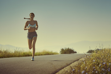 Femme sportive active en vêtements de sport d& 39 été courant, sprintant sur une route au lever ou au coucher du soleil. Soins de santé, soins du corps, mode de vie sain, concept de volonté. Édition de couleur tonique.