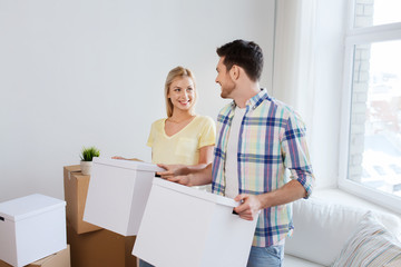 smiling couple with big boxes moving to new home