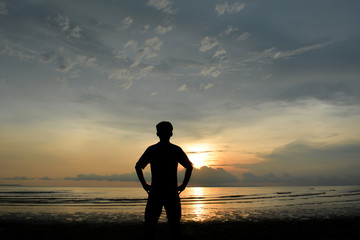 silhouette man akimbo. background sunset at sea.