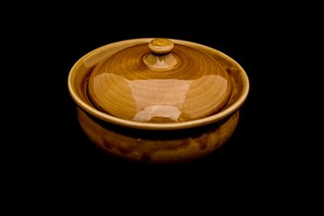 empty yellow ceramic bowl with cover isolated on black background - low key image